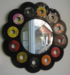 a round mirror with many different colored discs on the front and back of it, hanging on a wall