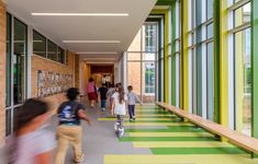 people are walking down the hallway in front of large windows and colorful stripes on the floor