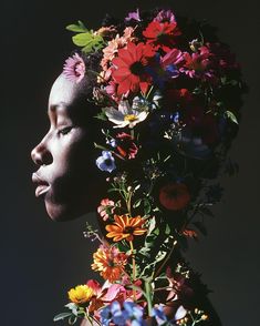 a woman with flowers on her head in front of a dark background, looking to the side