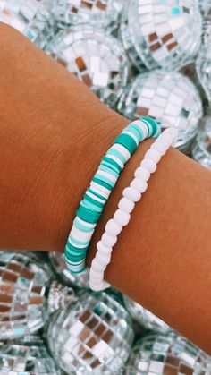 a close up of a person's arm wearing a bracelet with white and green beads