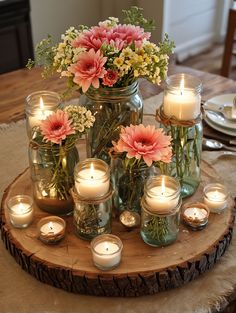 flowers and candles are arranged in mason jars on a table