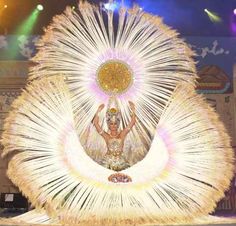 a woman dressed in white and gold dancing on stage