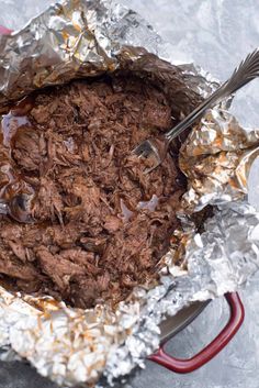 a red handled spoon is in a tin foil pan filled with brownies and other food