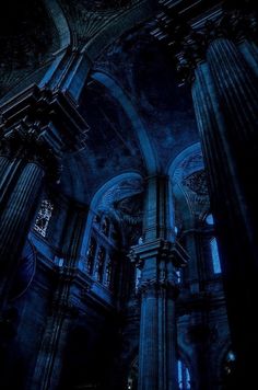 the interior of an old church with columns and stained glass windows in blue light from below