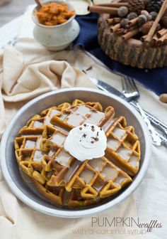 a waffle topped with icing in a bowl next to a fork and knife