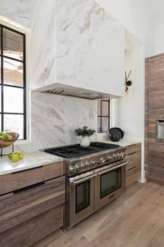 a kitchen with marble counter tops and stainless steel stove top, oven hood, and cabinets