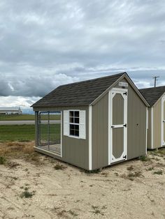 two small sheds in the middle of a field with grass and dirt on either side