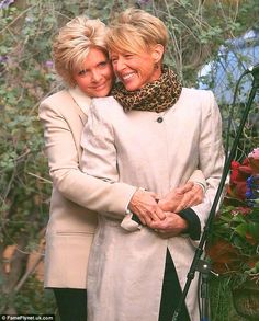 two women hugging each other in front of flowers