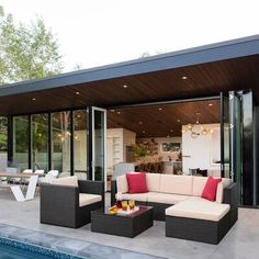 an outdoor living area with couches and tables next to a swimming pool in the backyard