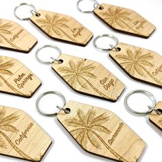 six wooden key chains with palm trees engraved on the front and back of each one