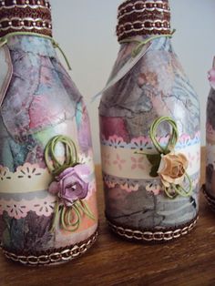 three decorative vases sitting on top of a wooden table with ribbons and flowers in them