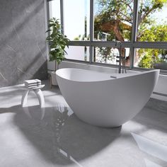 a white bath tub sitting next to a window in a room with large glass windows