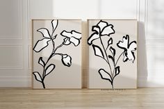 two black and white flowers are on the wall next to each other in an empty room