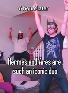 two men in costumes are standing on a couch with their arms up and one is wearing a cat mask