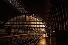 a train station with tracks and people waiting for the train to arrive at night time