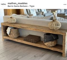 a wooden bench with baskets on top of it in front of a couch and mirror