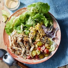 a plate filled with meat and vegetables on top of a wooden table next to utensils