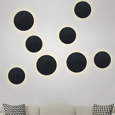 a white couch sitting in front of a wall with black circles on it's side