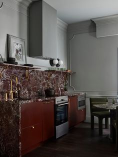 a kitchen with marble counter tops and red cabinetry, along with a dining room table