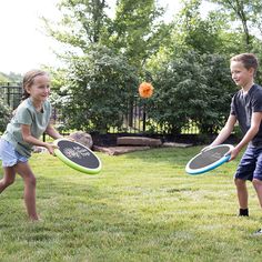 two children are playing with frisbees in the yard