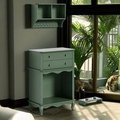 a green cabinet sitting next to a window with a cat on the floor in front of it