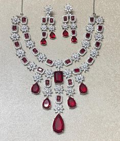 Ruby Necklace features a striking red stone and American diamond accents, inspired by Sabyasachi designs.  The intricate craftsmanship and luxurious look make it a perfect statement set for brides. Ideal for an Indian wedding, this elegant piece is a memorable gift for the bride. *𝐏𝐑𝐎𝐃𝐔𝐂𝐓 𝐃𝐄𝐓𝐀𝐈𝐋* * Material: Brass * Plating: White Rhodium Plated * Stone: Ruby And Diamond *𝐃𝐈𝐌𝐄𝐍𝐒𝐈𝐎𝐍𝐒* *𝐍𝐞𝐜𝐤𝐥𝐚𝐜𝐞* * 𝐖𝐞𝐢𝐠𝐡𝐭: 102 gm  * Drop 𝐋𝐞𝐧𝐠𝐭𝐡: 8 Inches * 𝐖𝐢𝐝𝐭𝐡: 4.3