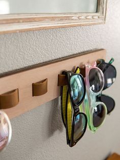 several pairs of sunglasses are hanging on the wall with eyeglasses attached to it