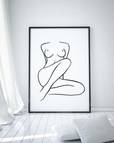 a black and white drawing of a naked woman in a frame on the wall next to pillows