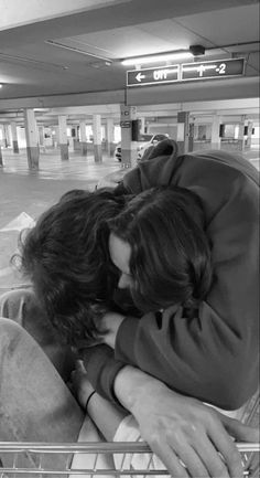 a man and woman are hugging in a shopping cart at an empty parking garage area