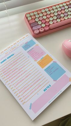 a pink computer keyboard sitting on top of a desk next to a mouse and paper