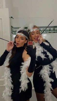 two women dressed in costumes taking pictures with their cell phones and holding wands while standing next to each other