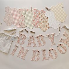 baby shower decorations laid out on a white table with clothes pins and sewing needles next to them