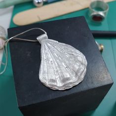 a silver sea shell on a black box