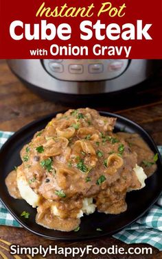 the instant pot cube steak with onion gravy is served on a black plate