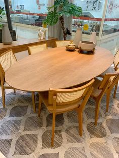 a large wooden table with chairs around it in a room filled with windows and plants