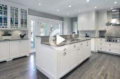 a large kitchen with white cabinets and granite counter tops, hardwood flooring, and stainless steel appliances