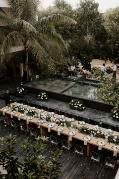 a long table is set up with white flowers and place settings for an outdoor wedding