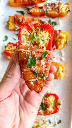 a person holding up a piece of food in front of some other foods on a plate