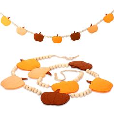 a necklace made out of felt and beads with pumpkins hanging from the strings on a white background