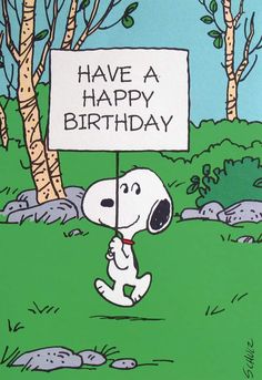 a snoopy holding a sign that says have a happy birthday with trees in the background