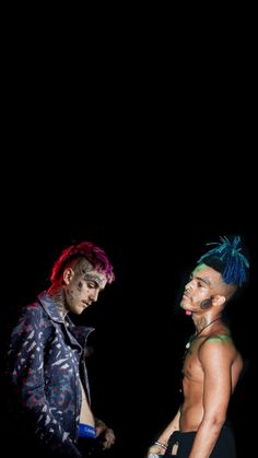 two men standing next to each other in front of a black background, one with dyed hair and the other without