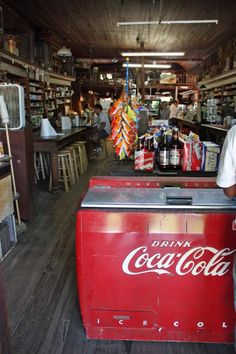 a man standing next to a red cooler in a room filled with shelves and tables