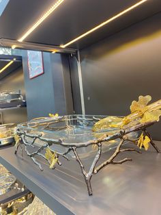 a glass tray with yellow flowers on it sitting on a table in a room filled with plates and bowls