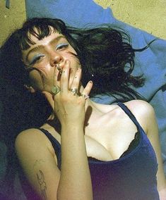 a woman laying on top of a bed with her hands in her mouth and eyes closed