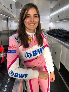 a woman in pink and white racing suit posing for the camera