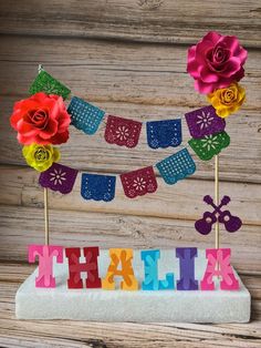 a cake that is decorated with flowers and the word thank spelled in colorful letters on top