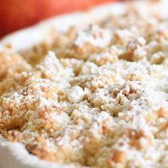 an apple pie with powdered sugar on top in a white casserole dish