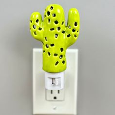 a green cactus shaped light switch cover on a white electrical outlet with holes in it