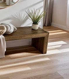 a wooden bench sitting in front of a mirror on top of a hard wood floor