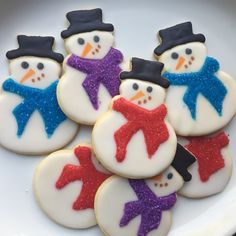 snowman cookies decorated with royal icing are on a white plate, ready to be eaten